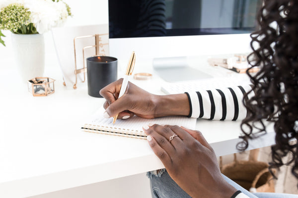 Professional woman writing goals in a planner at an organized desk