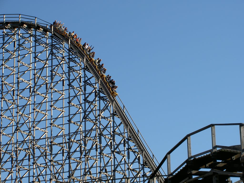 Experience the exhilarating thrill of a roller coaster ascending the steep peak at an amusement park.